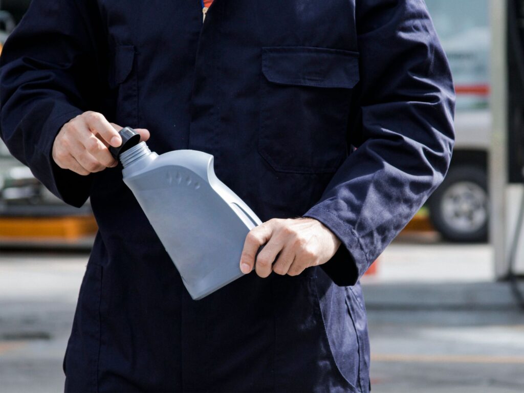 a man in a blue uniform holding a bottle of fuel