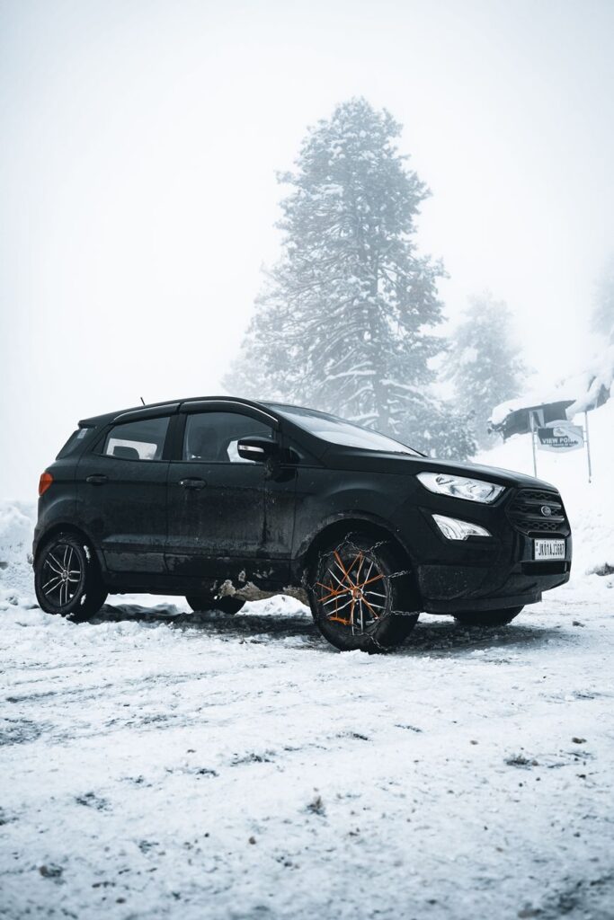 black suv parked on snow covered ground near pine tree